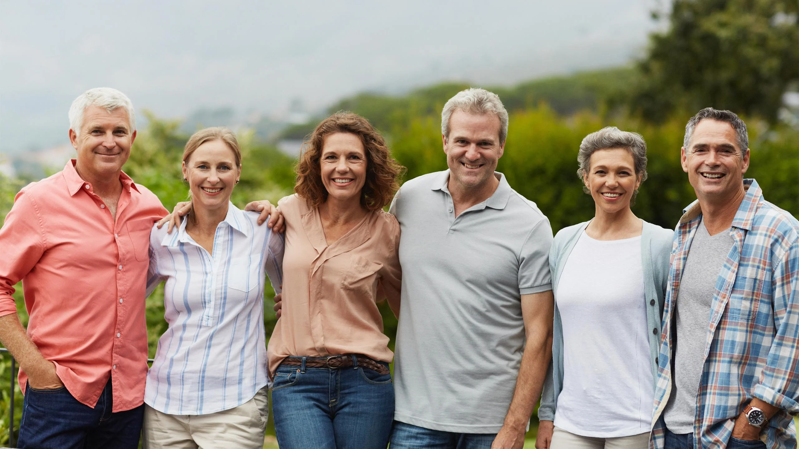 Six happy, supportive people standing together, outdoors.